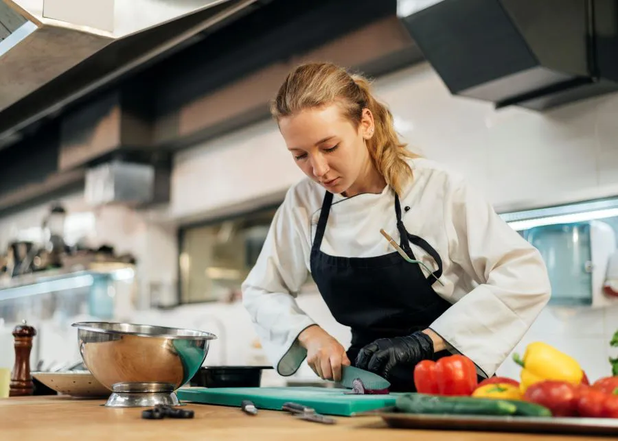 female-chef-chopping-vegetables-kitchen-scaled